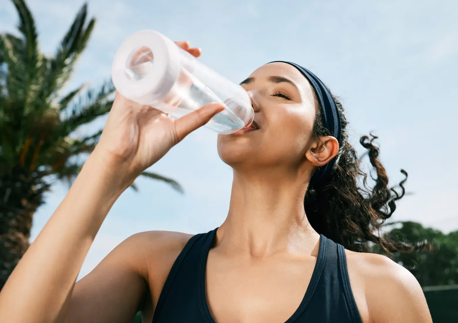Woman drinking water to stay cool while she's outside